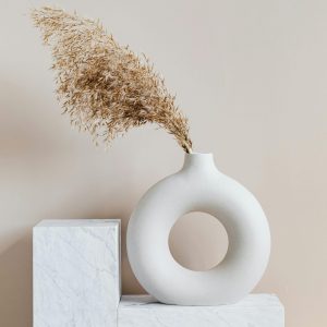 Round donut style white vase filled with pampas grass