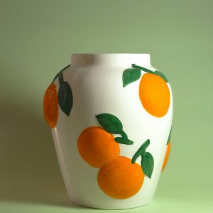 large white tall oval shape vase designed with large oranges with dark green leaves painted on
